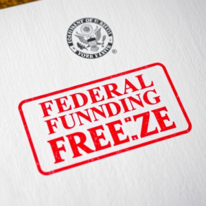 An official-looking government document with the words 'Federal Funding Freeze' stamped in red, symbolizing halted financial assistance
